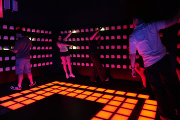 Group playing interactive light room game with LED wall and floor at Power Play Sydney venue